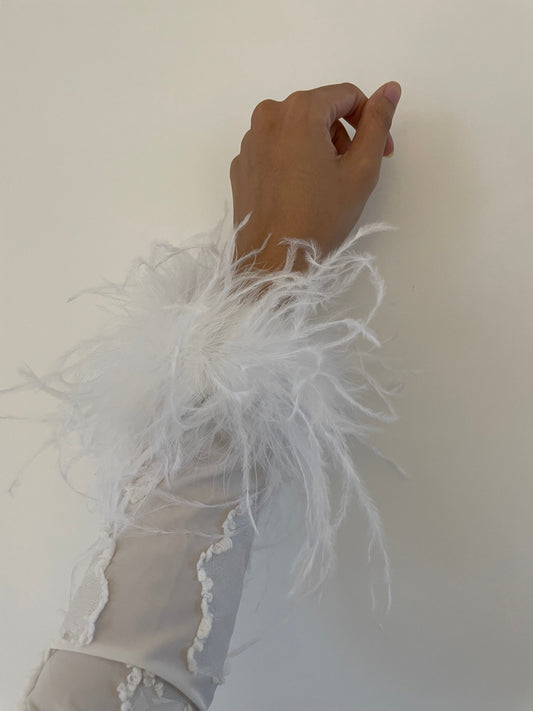 Showing a close up look of our white feather cuffs styled on a white dress 